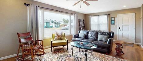 A living room with a sofa, armchairs, a coffee table, and a patterned rug.