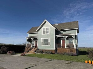 A two-story house with a porch, a front staircase, and a driveway. - 1858 Homestead - Historic Country Retreat with Modern Comforts (Ferndale)
