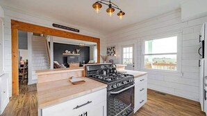 Una cucina con isola centrale, pavimento in legno e vista all'esterno.