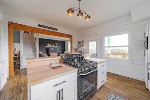A kitchen with a central island, wooden flooring, and a view to the outside. - 1858 Homestead - Historic Country Retreat with Modern Comforts (Ferndale)