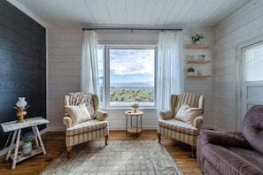 A room with two striped armchairs facing a window, a small round table, and a purple sofa. - 1858 Homestead - Historic Country Retreat with Modern Comforts (Ferndale)