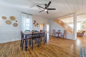 A dining area with a wooden table and chairs, a ceiling fan, and a staircase leading to another level. - 1858 Homestead - Historic Country Retreat with Modern Comforts (Ferndale)