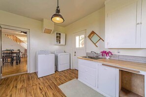 Une cuisine avec des armoires blanches, un plan de travail en bois, un évier et un luminaire suspendu.