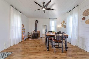 A dining area with a wooden table and chairs, a ceiling fan, and a fireplace. - 1858 Homestead - Historic Country Retreat with Modern Comforts (Ferndale)