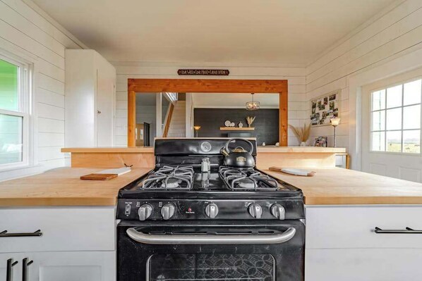 Une cuisine avec un poêle noir, un plan de travail en bois et un grand miroir au-dessus du poêle.