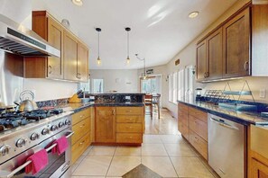 A modern kitchen with wooden cabinets, stainless steel appliances, and pendant lighting.