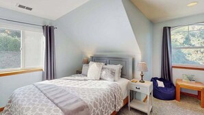Ein Schlafzimmer mit Bett, Nachttisch, Lampe und Blick ins Freie.