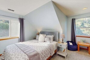 Ein Schlafzimmer mit Bett, Nachttisch, Lampe und Blick ins Freie.