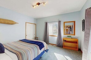 Quarto com cama, mesa de cabeceira, espelho e janela com cortinas.