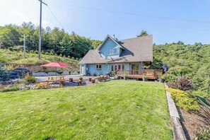 A two-story house with a deck, a covered patio, and a well-maintained lawn.