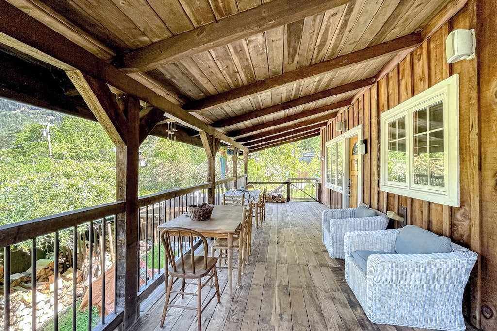 Une terrasse en bois avec une table et des chaises, donnant sur une zone boisée.