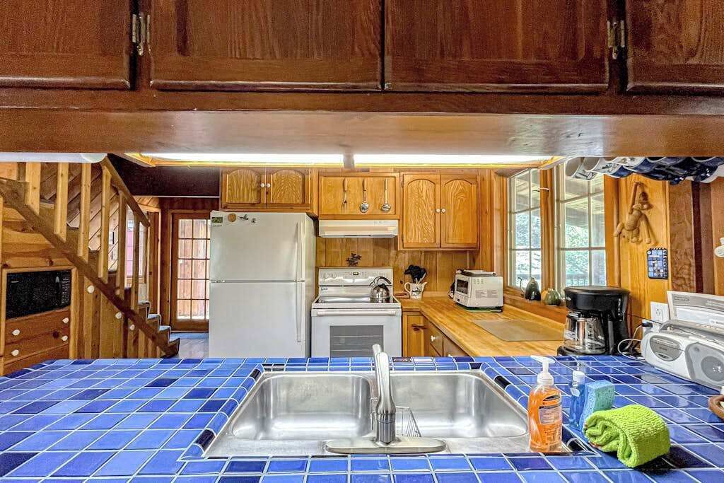 A kitchen with wooden cabinets, a stainless steel sink, and a blue-tiled countertop.