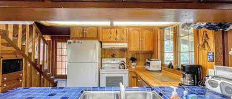 A kitchen with wooden cabinets, a stainless steel sink, and a blue-tiled countertop.