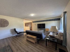 A modern living room with a flat-screen TV, a sofa, a bench, and a coffee table.