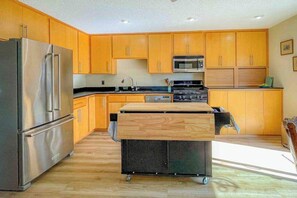 A modern kitchen with wooden cabinets, stainless steel appliances, and a central island with a sink.