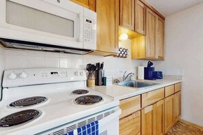 A kitchen with a white stove, microwave, and wooden cabinets.