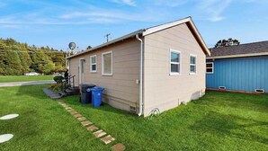 Ein eingeschossiges Haus mit geneigtem Dach, einer Veranda und einer kleinen angebauten Garage.