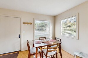 A dining area with a table, chairs, and a window with blinds.