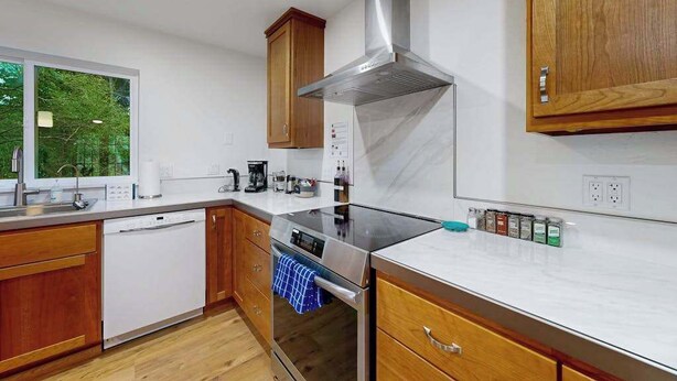Una cocina moderna con armarios de madera, una campana extractora de acero inoxidable y un horno empotrado.