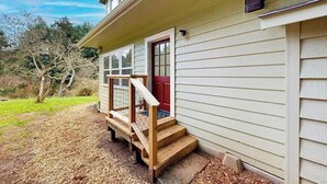 Una casa de dos pisos con una escalera de madera que conduce a una puerta roja.