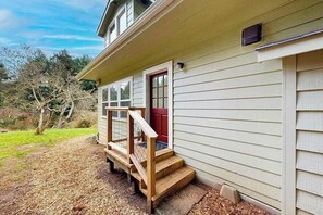 Ein zweistöckiges Haus mit einer Holztreppe, die zu einer roten Tür führt.