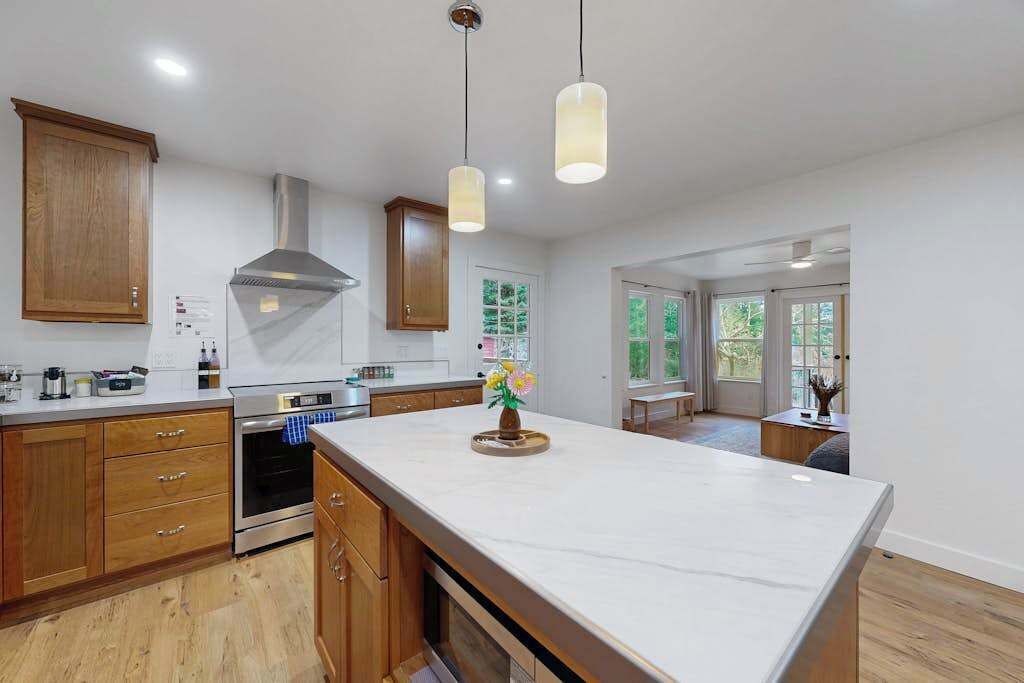 A modern kitchen with wooden cabinets, a central island, and pendant lighting.
