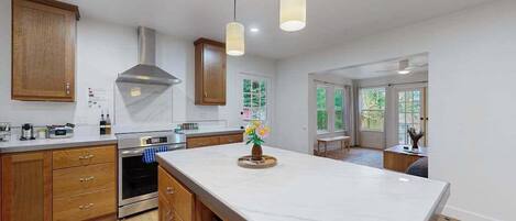 A modern kitchen with wooden cabinets, a central island, and pendant lighting.