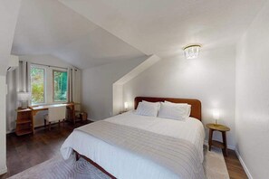 Ein Schlafzimmer mit einem großen Bett, einem Schreibtisch und einem Fenster.