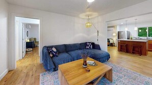 Un espacio habitable moderno con un sofá, una mesa de centro y una cocina con barra.