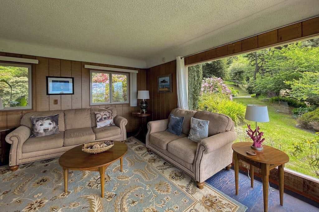 Una sala de estar con dos sofás, una mesa de centro y vistas a un jardín.