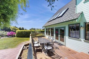 Eine überdachte Terrasse mit Tisch und Stühlen, ein Holzboden und ein Haus mit Dachfenster.