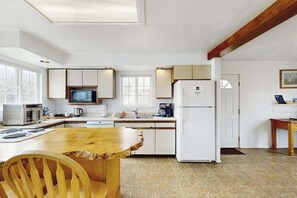 Une cuisine moderne avec des appareils électroménagers blancs, un îlot central en bois et une grande fenêtre.