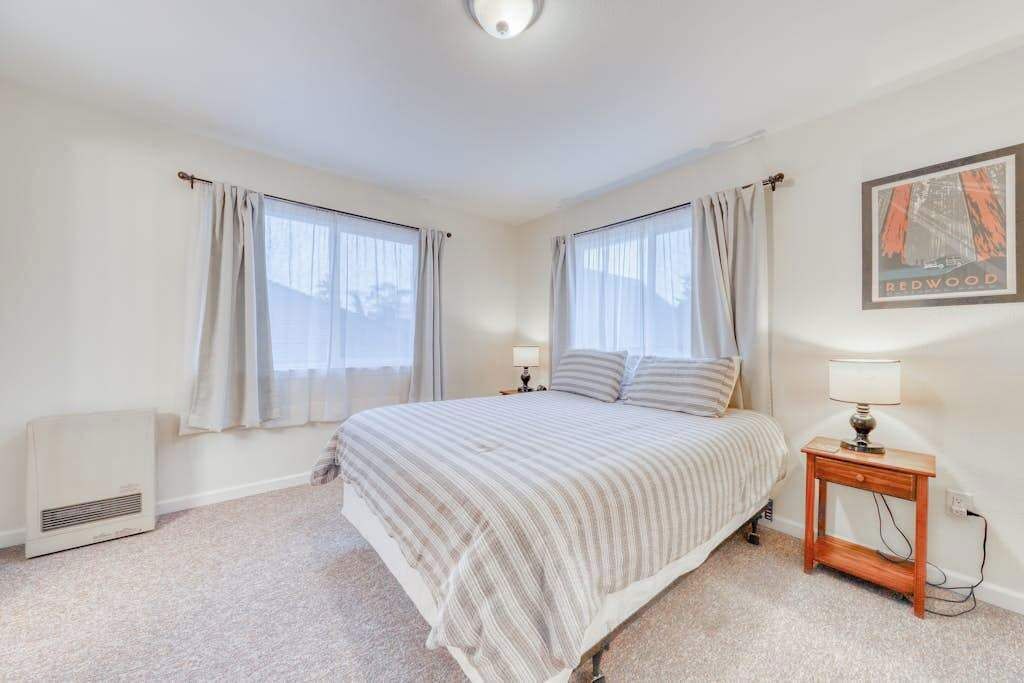 Une chambre à coucher avec un lit, deux tables de chevet, une lampe et un radiateur.