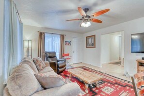 A living room with a sofa, a coffee table, a ceiling fan, and a television. - Seventh Street Select (Eureka)
