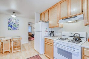 A kitchen with wooden cabinets, a white refrigerator, a stove, and a kettle. - Seventh Street Select (Eureka)