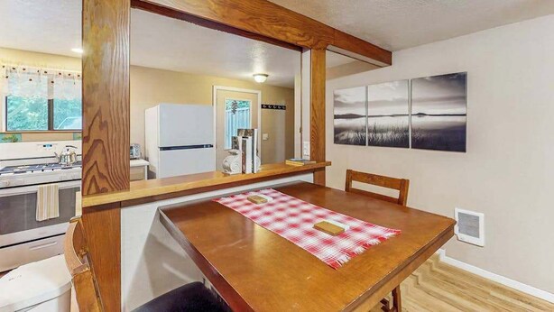 A dining area with a wooden table, chairs, and a red checkered placemat. - Peaceful Creekside - Tranquil Nature Retreat by the Water (Trinidad)