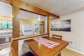 A dining area with a wooden table, chairs, and a red checkered placemat. - Peaceful Creekside - Tranquil Nature Retreat by the Water (Trinidad)