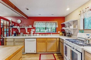 A compact kitchen with a dishwasher, stove, and sink. - Peaceful Creekside - Tranquil Nature Retreat by the Water (Trinidad)