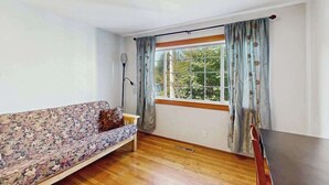A room with a sofa, a table, a window with curtains, and a lamp. - Eureka Charmer - Cozy Historic Getaway in the Heart of Town (Eureka)