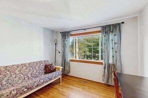 Ein Zimmer mit einer Couch, einem Tisch, einem Vorhangfenster und einer Lampe.