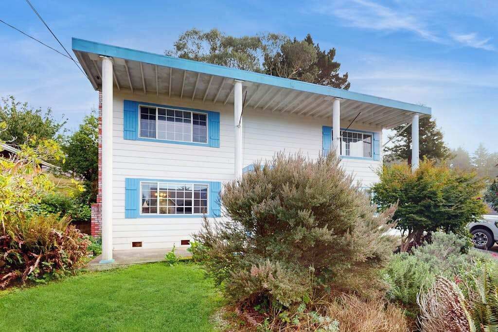 A two-story house with a covered porch and a well-maintained lawn.