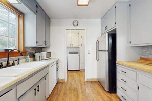 Une cuisine avec des meubles blancs, un four à micro-ondes, un réfrigérateur et un plan de travail en bois.