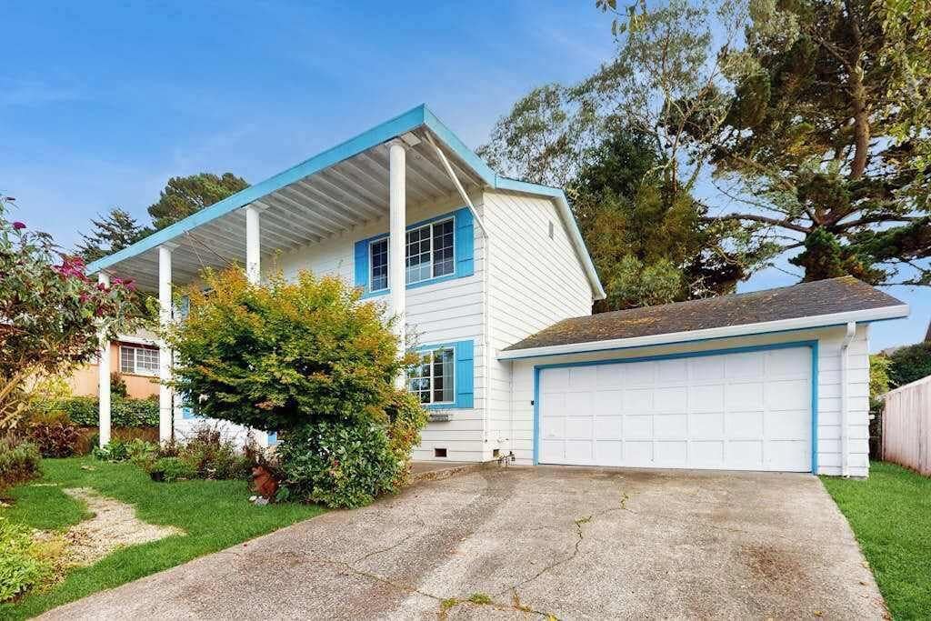 A two-story house with a garage, surrounded by a well-maintained lawn and trees.