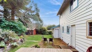 A residential property with a wooden deck, a grassy yard, and a white house with blue trim. - Eureka Charmer - Cozy Historic Getaway in the Heart of Town (Eureka)