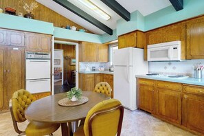 Eine Küche mit Holzschränken, einem Esstisch mit Stühlen und einem Kühlschrank.