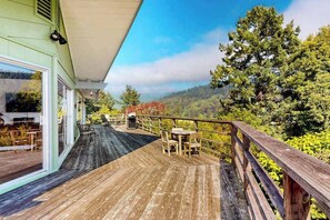 Eine Holzterrasse mit Gartenmöbeln, mit Blick auf eine bewaldete Landschaft.