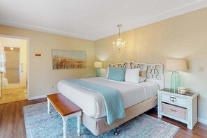 Ein Schlafzimmer mit Bett, Nachttisch, Bank und einem Gemälde an der Wand.