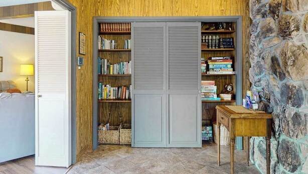 Una habitación con pared de madera, un armario gris y una pequeña mesa.