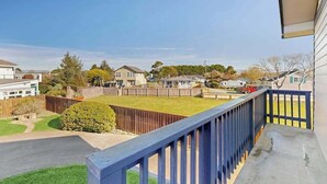 A residential area with a fenced backyard, a wooden deck, and houses in the background. - Pacific View Escape - Stunning Ocean Views & Coastal Comfort (Crescent City)