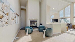 A spacious living area with a fireplace, seating, and artwork on the walls. - Pacific View Escape - Stunning Ocean Views & Coastal Comfort (Crescent City)